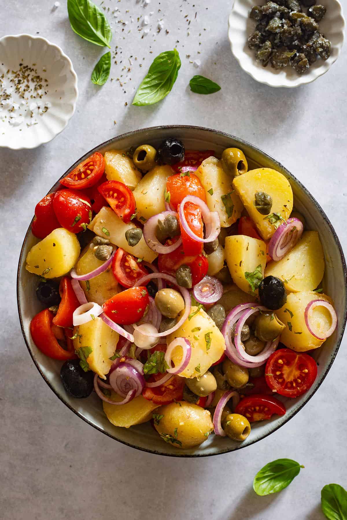 Insalata Pantesca, also known as Sicilian potato salad in a bowl with basil leaves scattered around.