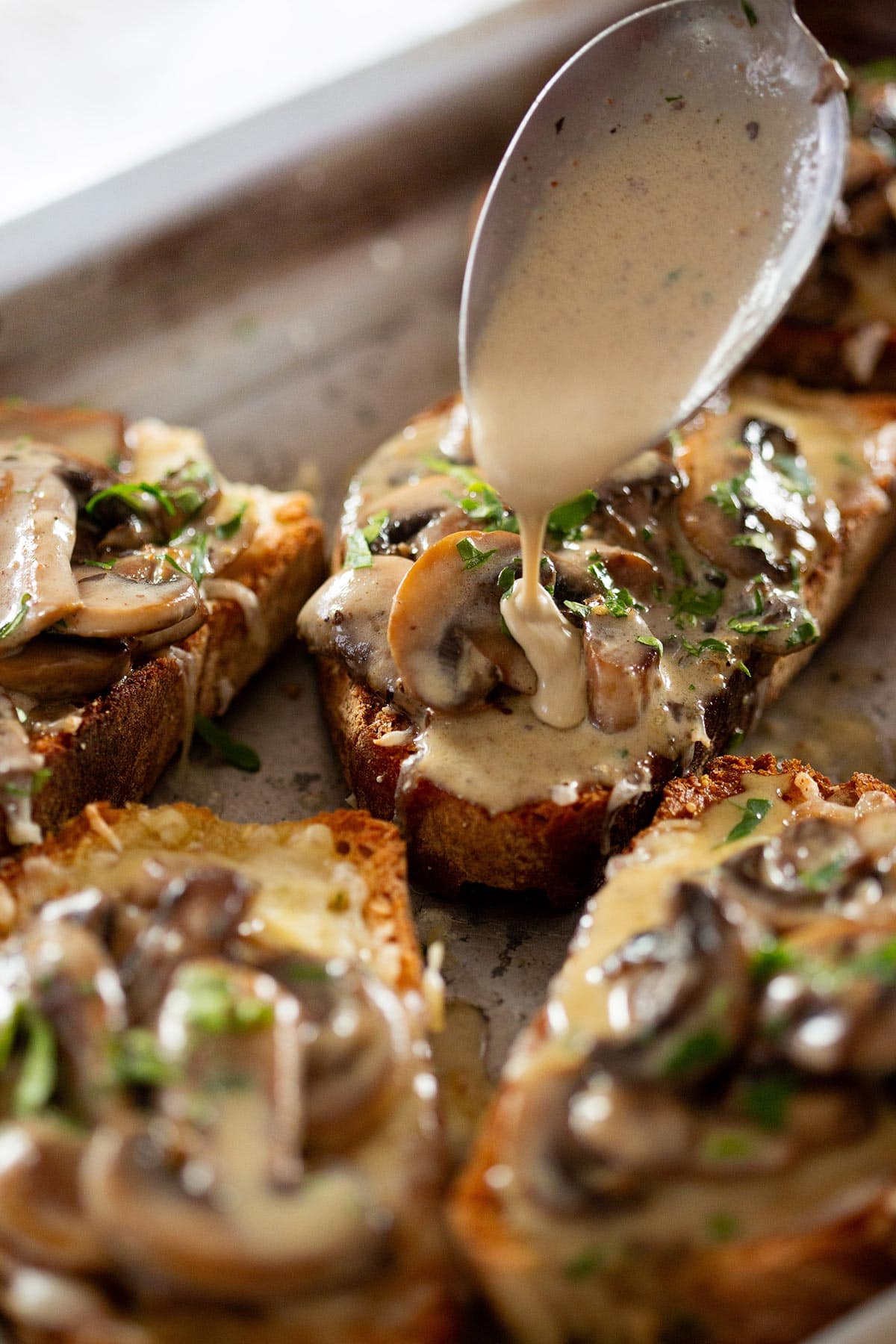 Bruschetta con funghi being drizzled with the creamy mixture.