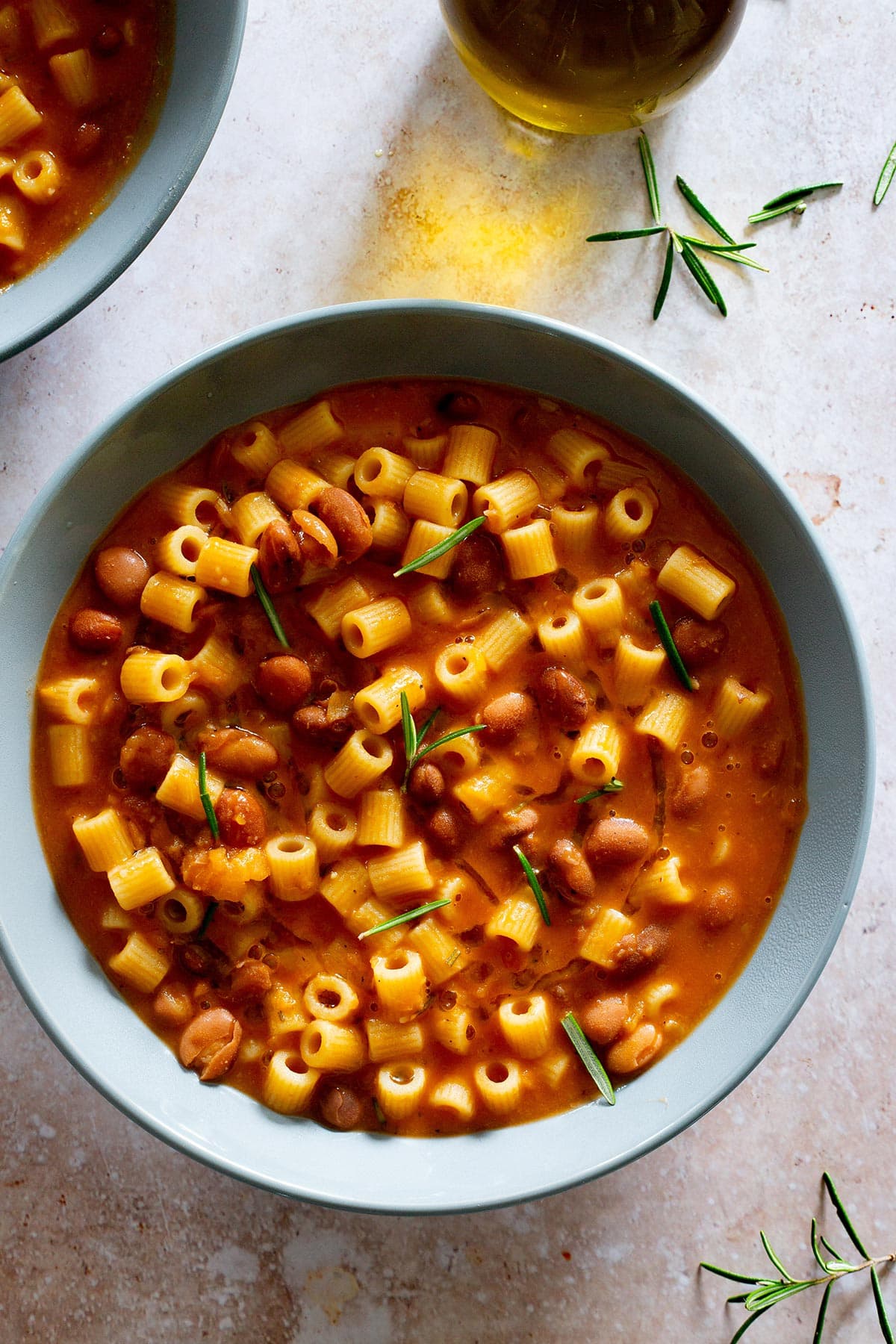 Creamy pasta e fagioli served in a bowl with fresh rosemary.