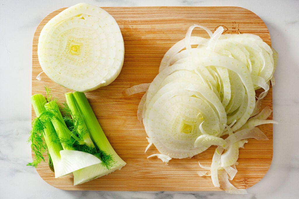 A cutting board with thinly sliced fennel.