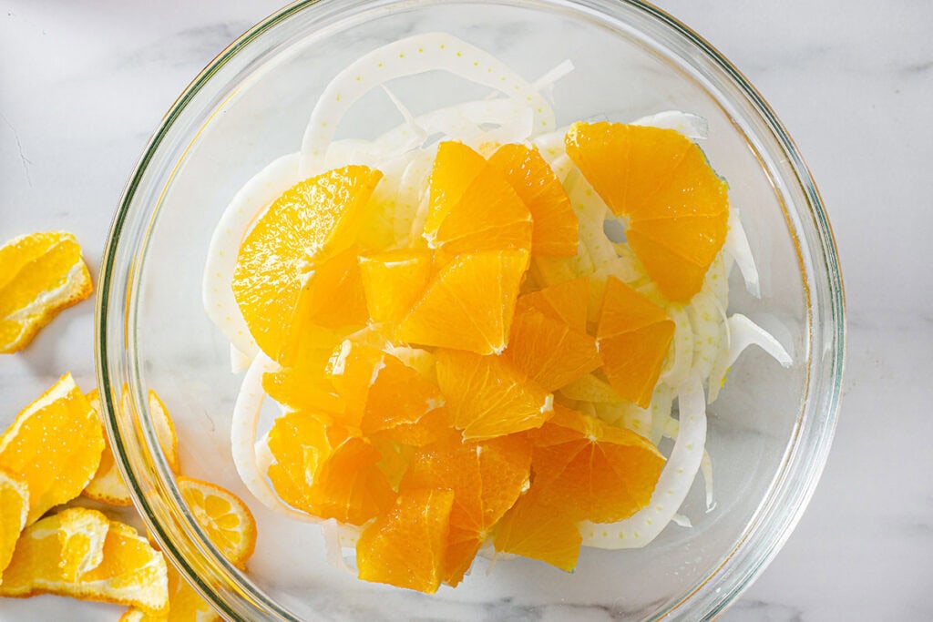 Sliced oranges added to the bowl with fennel.