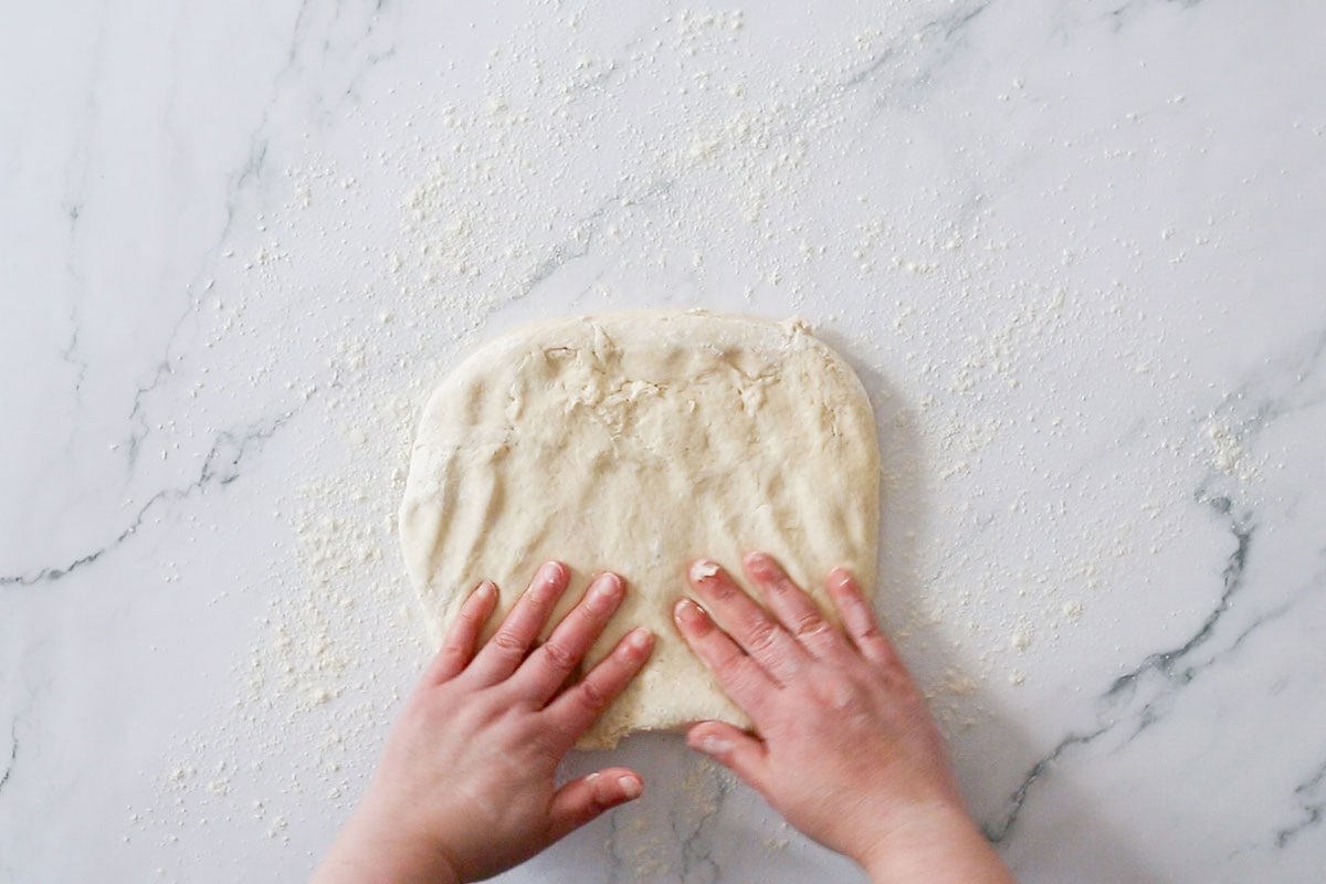 Flattening the dough with hands.