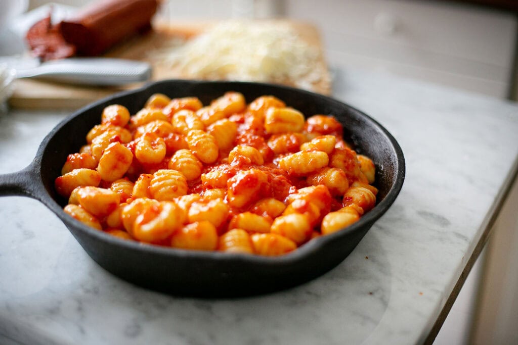 Gnocchi tossed with tomato sauce in a skillet.