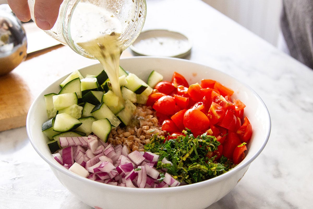 Adding the dressing over the ingredients for the salad in the bowl.