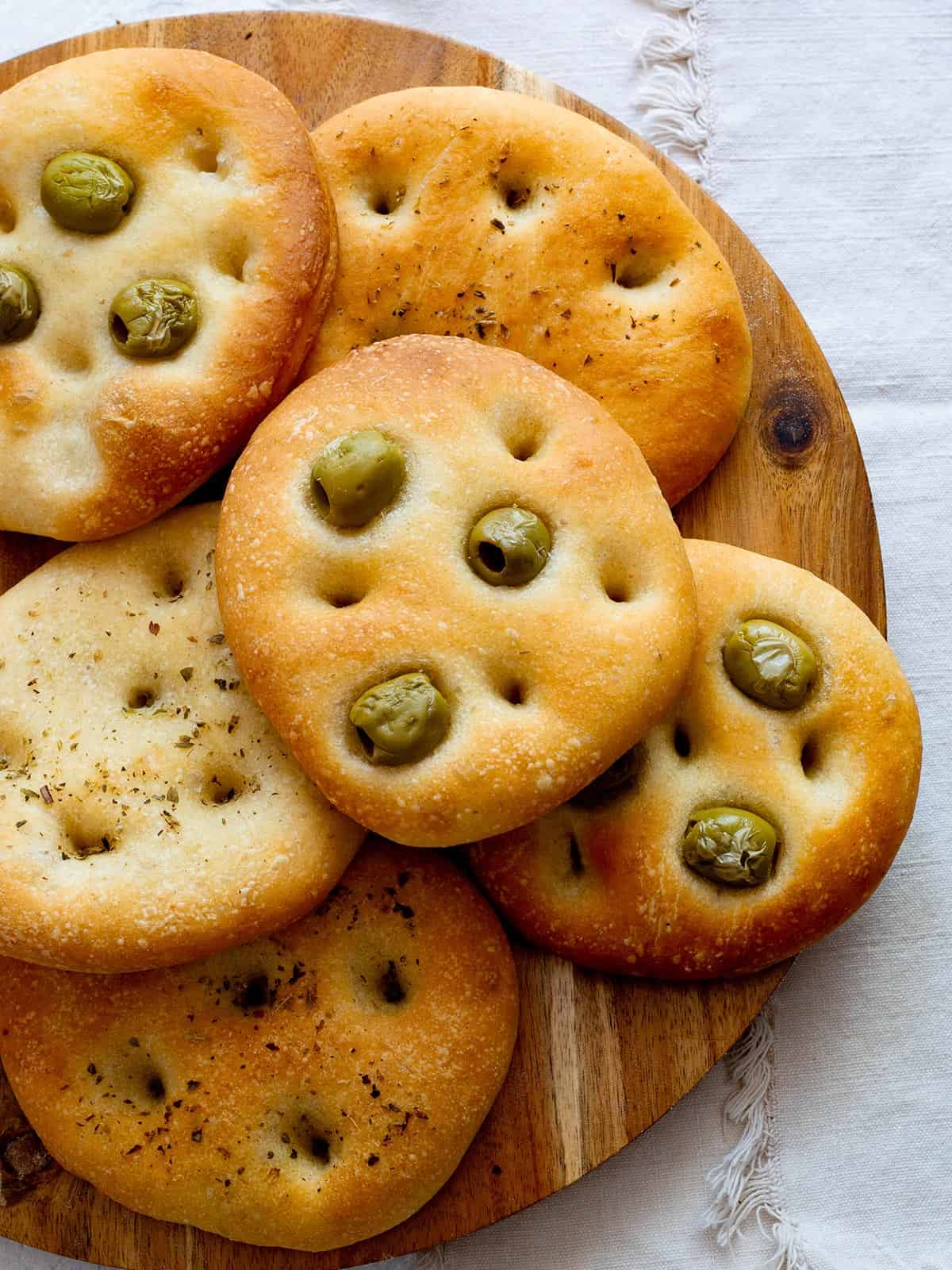 Focaccine with olives and oregano on a cutting board.