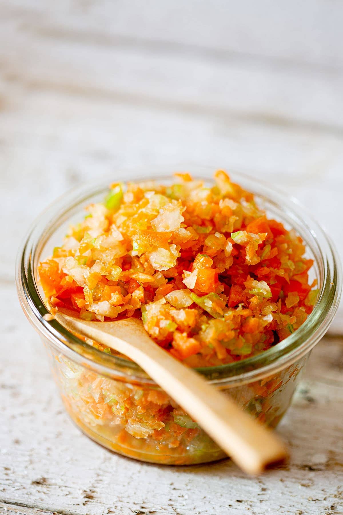 Soffritto mixture in a jar with a wooden spoon.