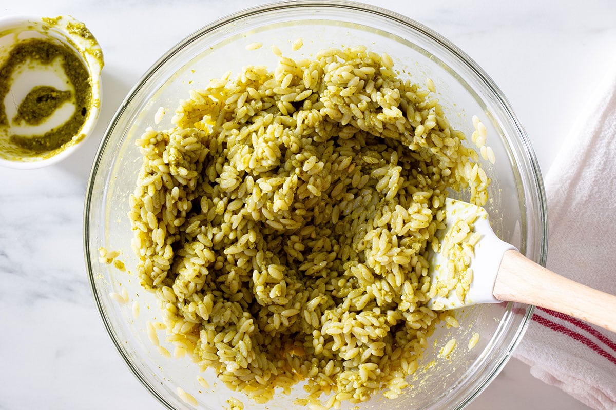 Orzo pasta and pesto mixed in a bowl.