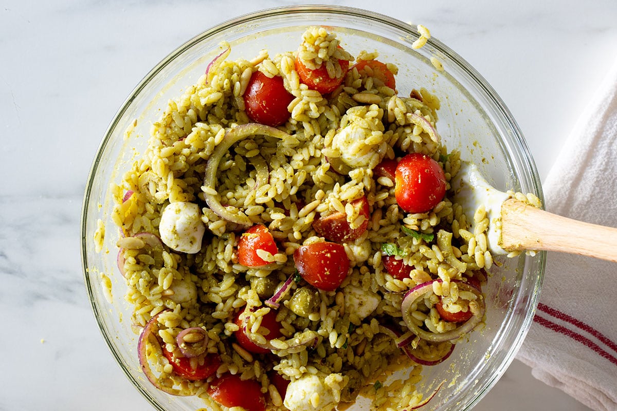 Orzo pesto salad with pesto fully prepared in a mixing bowl.