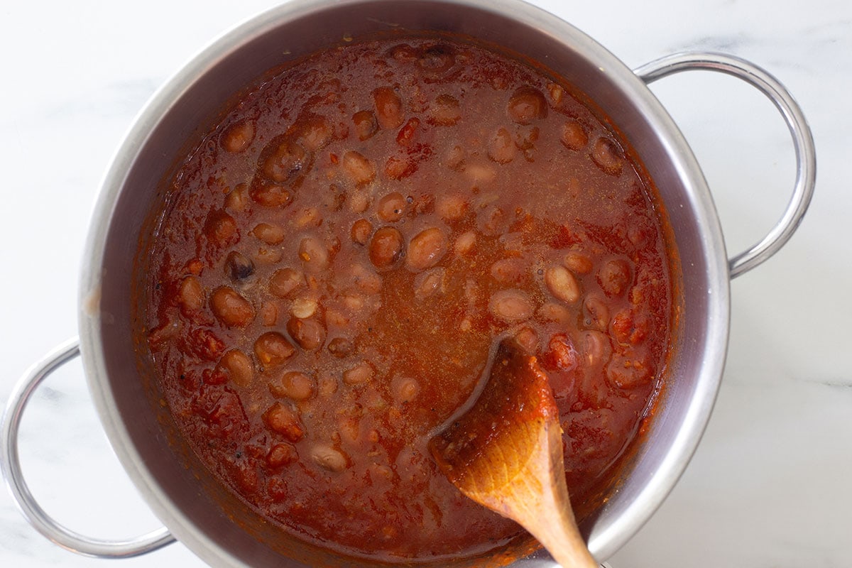 Cooking beans with the tomato sauce and flavorings in the pot.