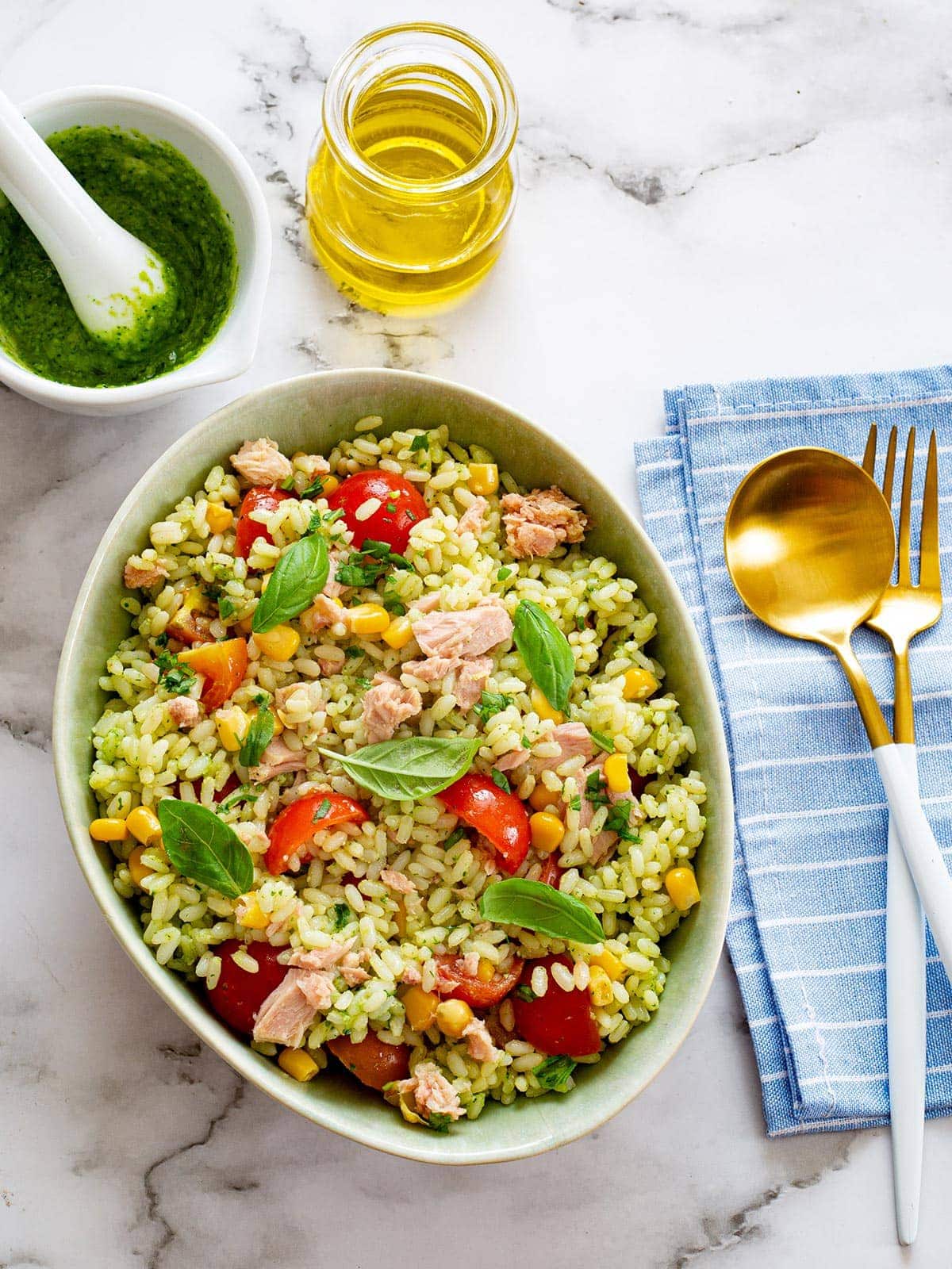 Pesto rice salad in a bowl and some ingredients on the side.