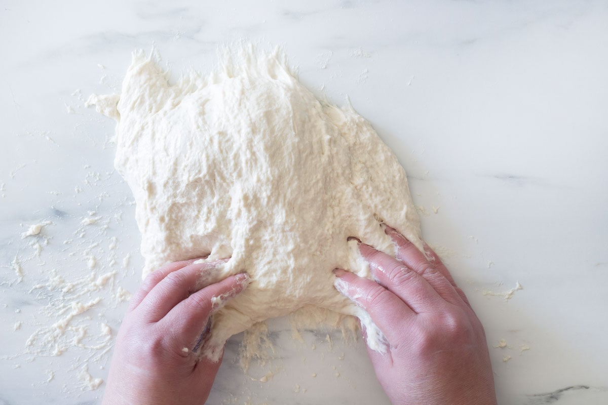 Kneading the sticky dough on an oiled surface.
