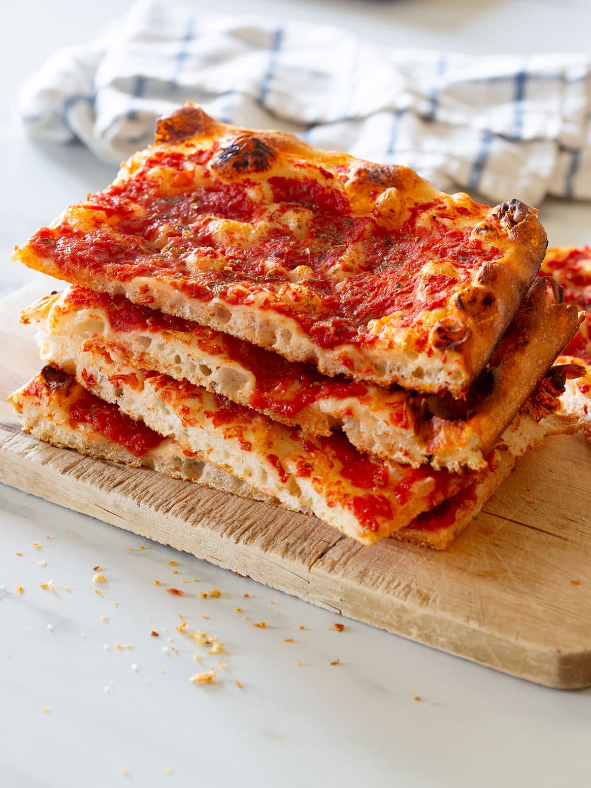 Pizza rossa cut into squares and piled on a cutting board.