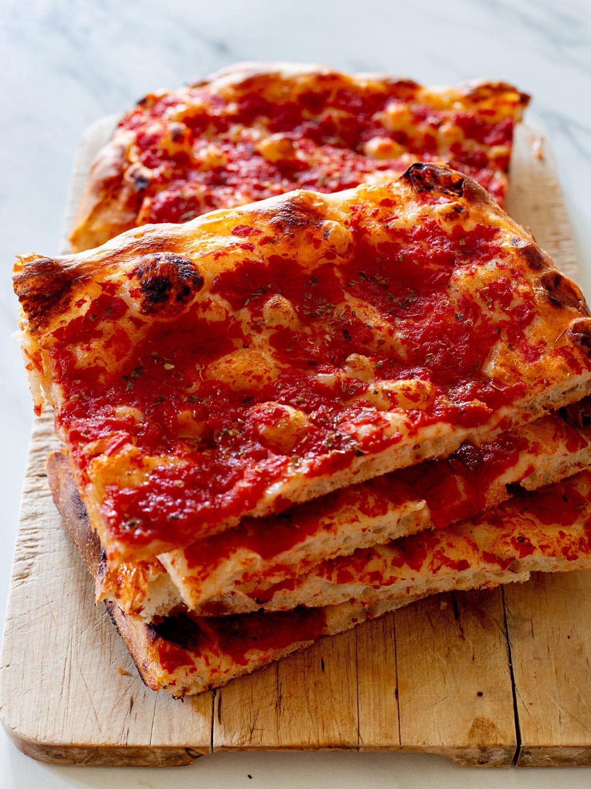 Pizza rossa sliced and piled on a cutting board.