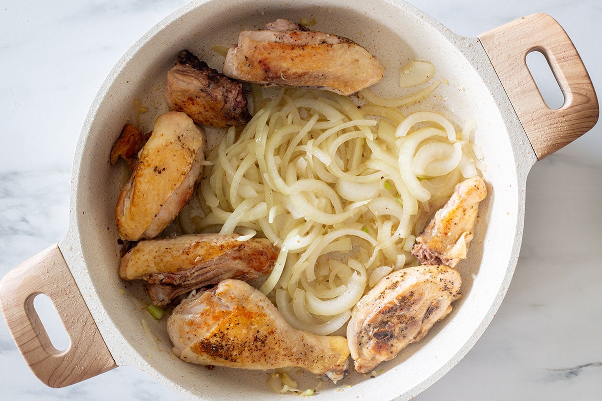 Chicken pieces moved to the sides of the pan and sauteed onion and garlic in the middle.