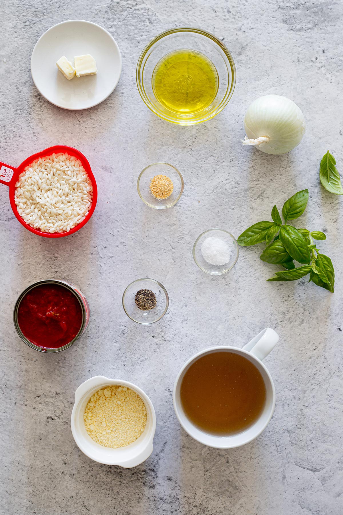 Ingredients for risotto al pomodoro displayed on a concrete surface.