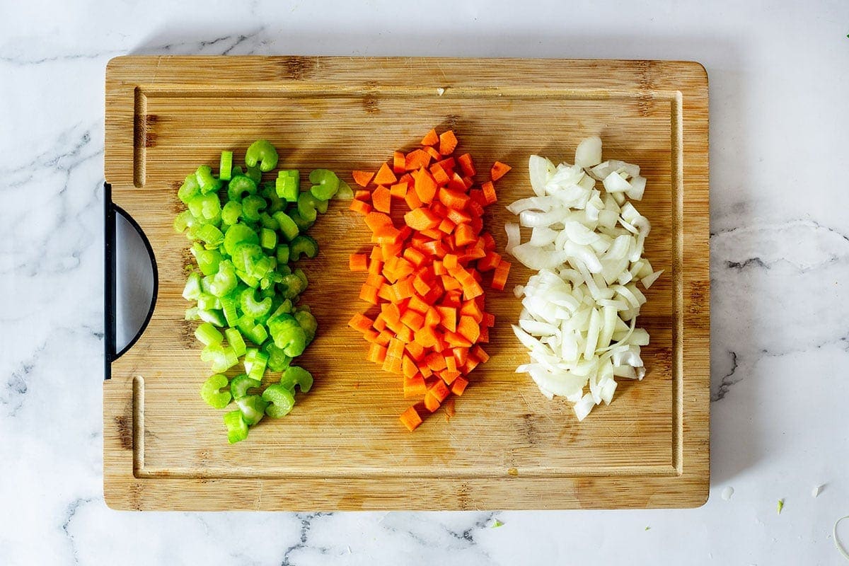 Diced celery, carrot, and onion on a cutting board.