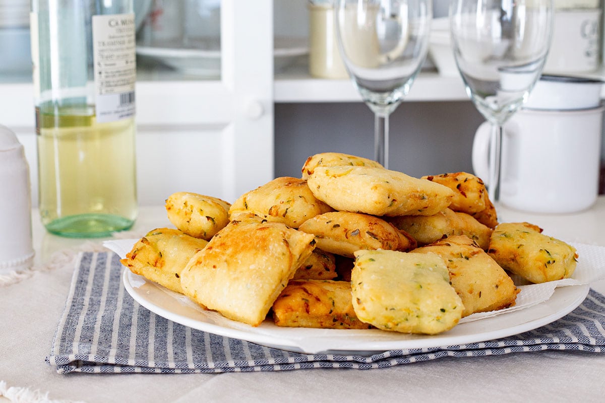 Zeppole di zucchine, also known as zeppoline, on a plate with a bottle of wine on the background.