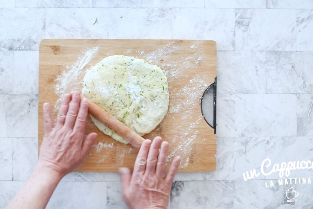 Rolling the zucchini dough with a rolling pin.