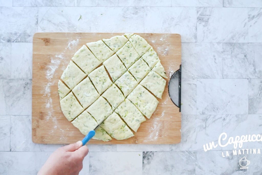 Cutting the raw zucchini zeppole with a pizza cutter.