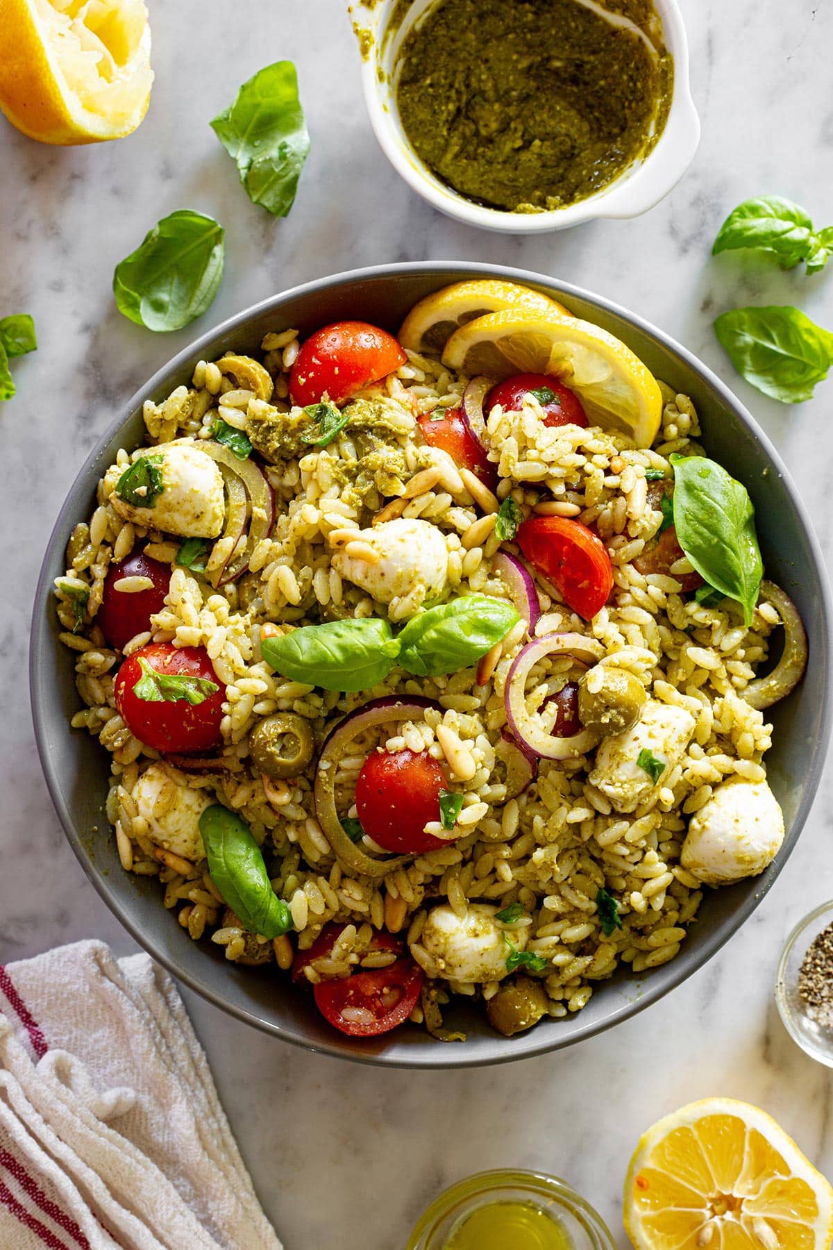 Orzo pasta salad with pesto in a grey bowl and a small bowl with pesto on the side.