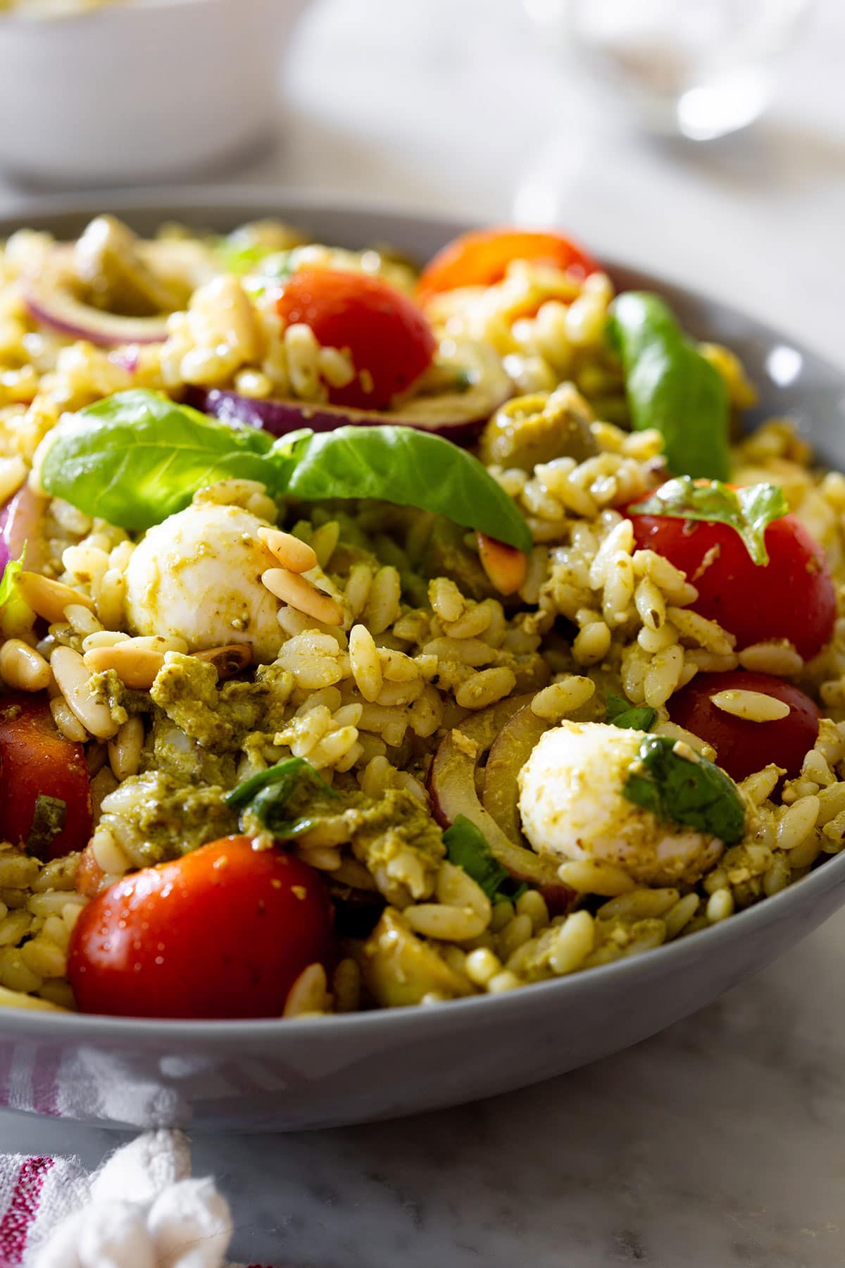 Orzo pasta salad with pesto served in a grey bowl.
