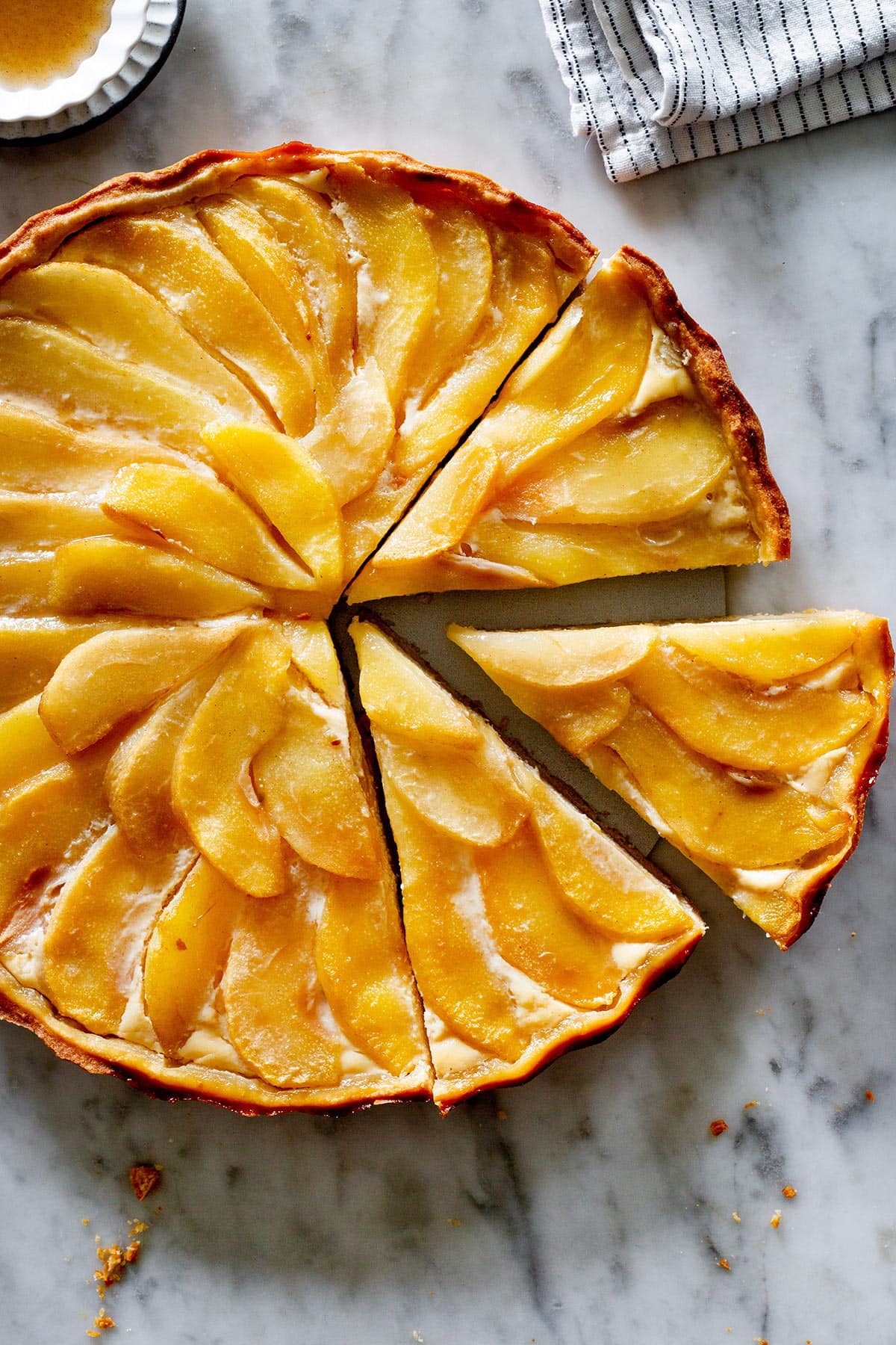 Crostata di pere (pear crostata) with two slices cut on a marble surface.