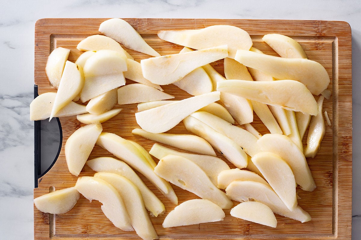 The pears sliced in wedges on a cutting board.