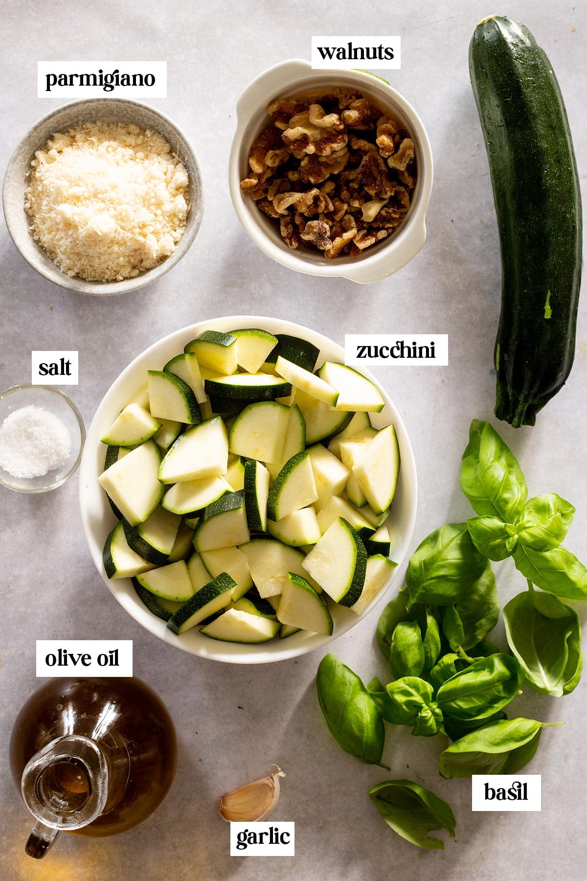 Ingredients for pesto di zucchine on a concrete kitchen surface.