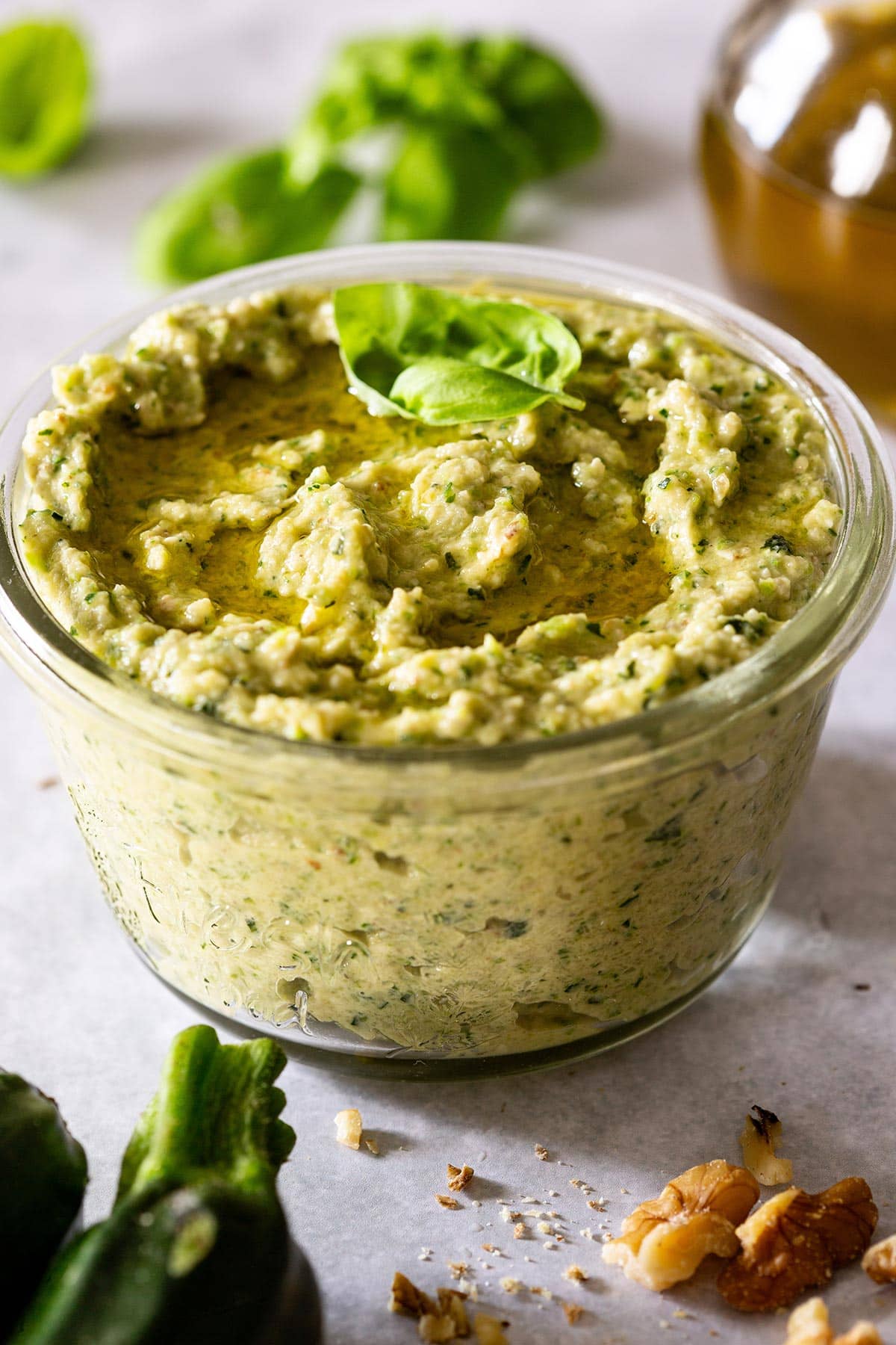 Pesto di zucchine in a jar with oil drizzled on top.