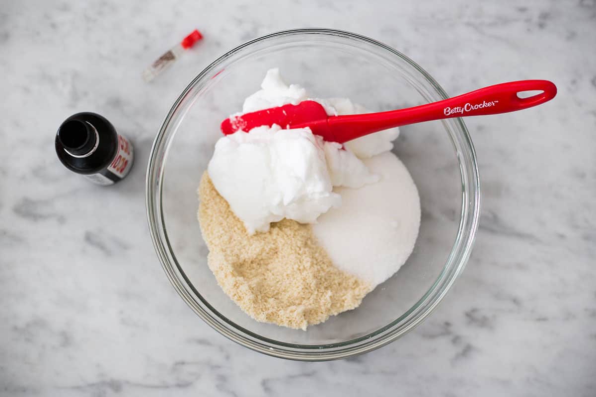 Ingredients for amaretti morbidi in a bowl with a red spatula.
