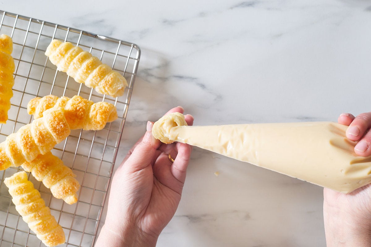 Filling a cannoncino pastry with pastry cream.