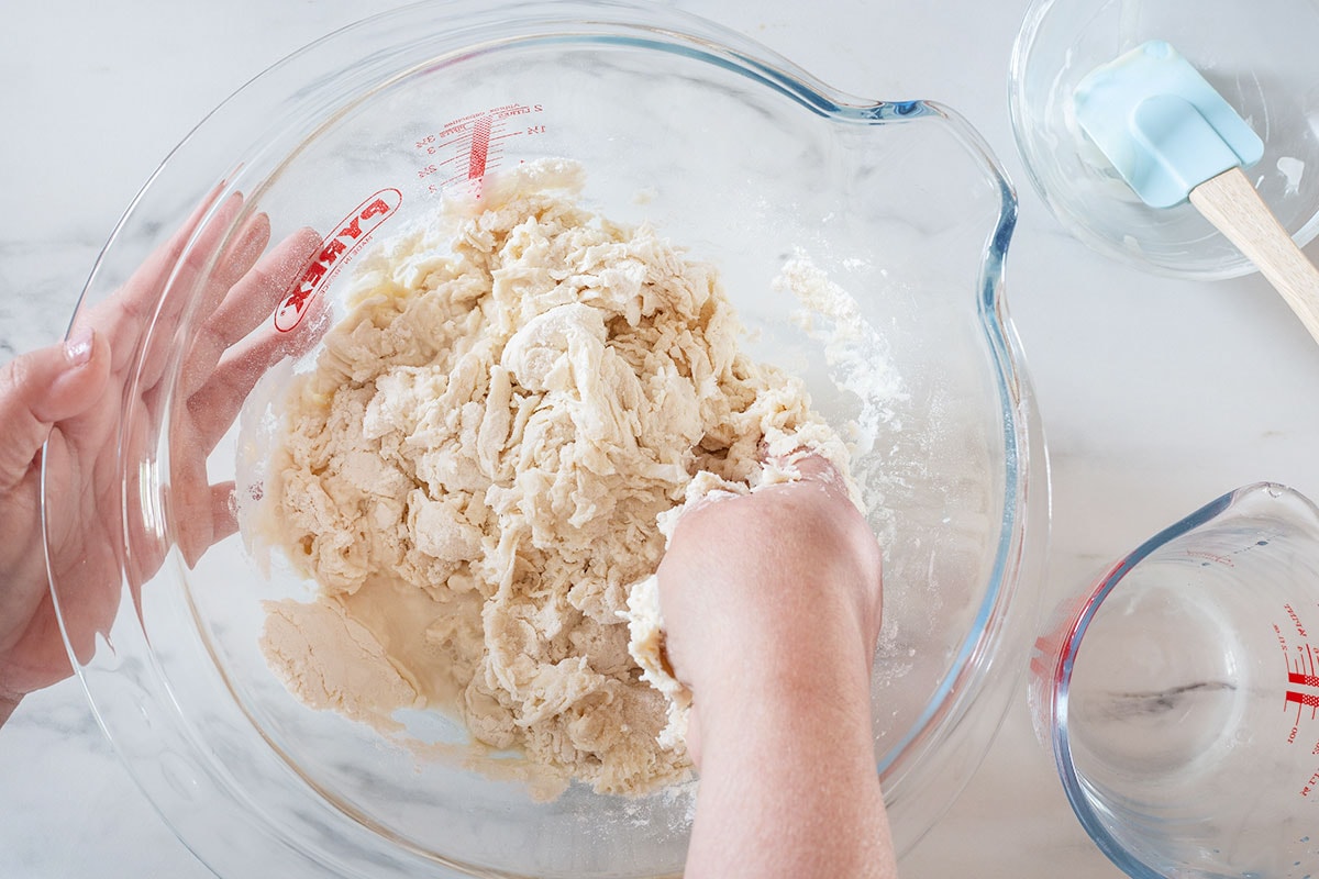 Preparing the dough with hands in a bowl.