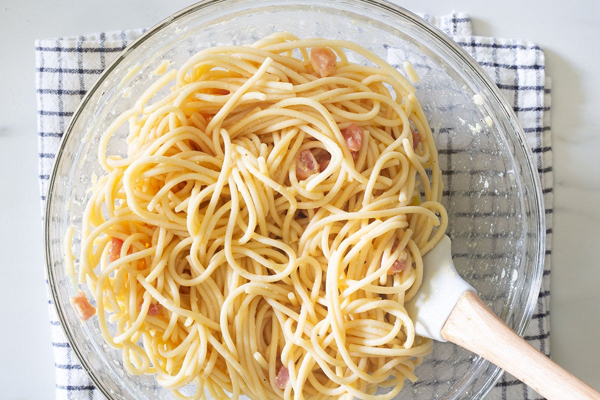 Added cooked spaghetti into the bowl with whisked eggs.