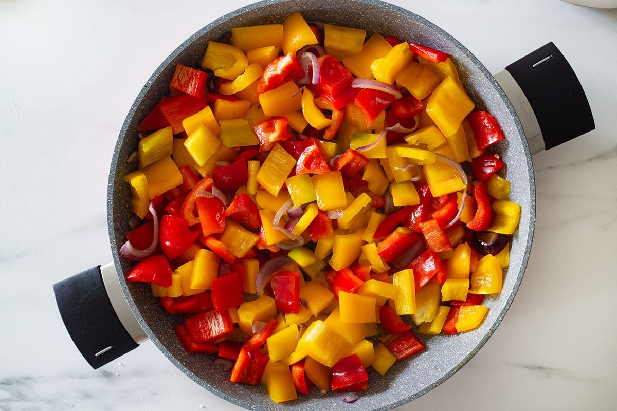 The peppers and onions in a pan.