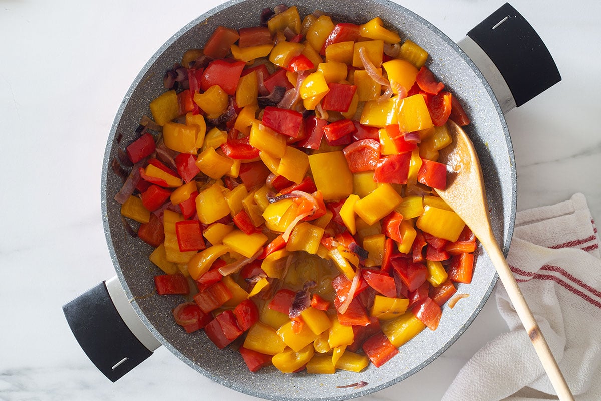 The cooked onions and peppers mixture in a pan.