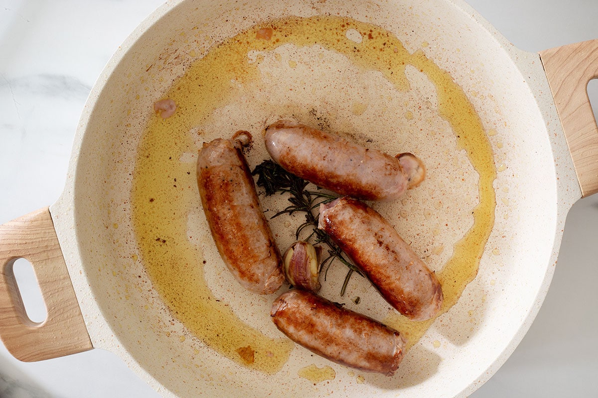 Browned sausages in a pan.