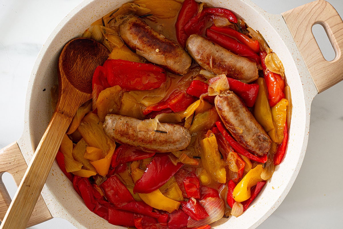 Fully cooked sausage and bell peppers (peperoni e salsicce) in a pan.