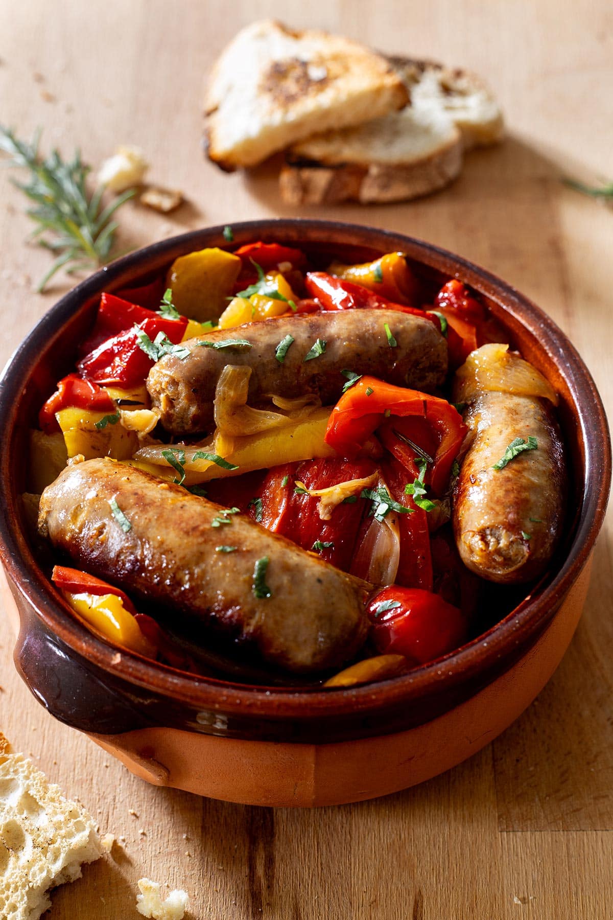 Peperoni e salsicce in a terracota pan.