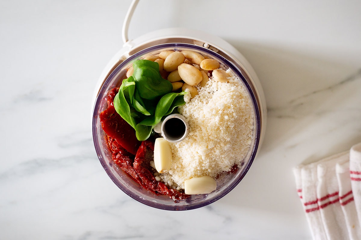 All ingredients for pesto  in a food processor.