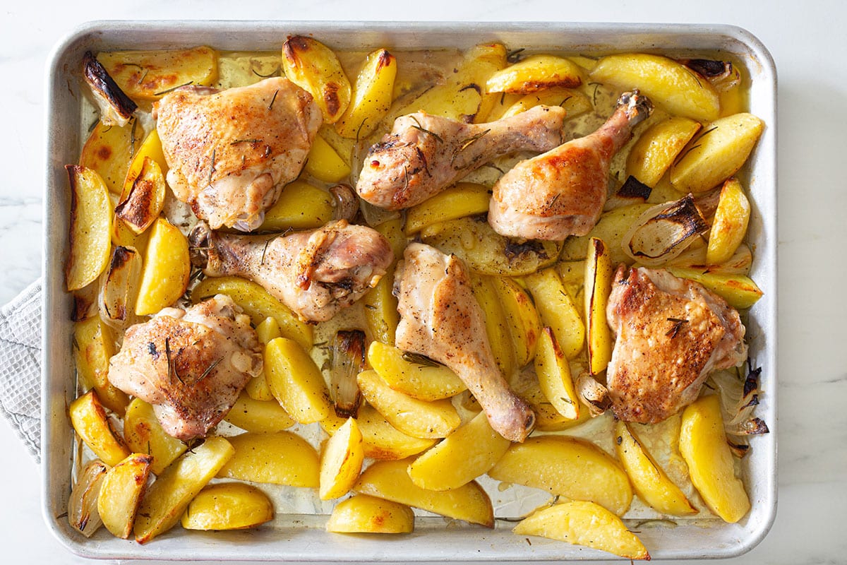 Fully baked pollo con le patate in a tray.