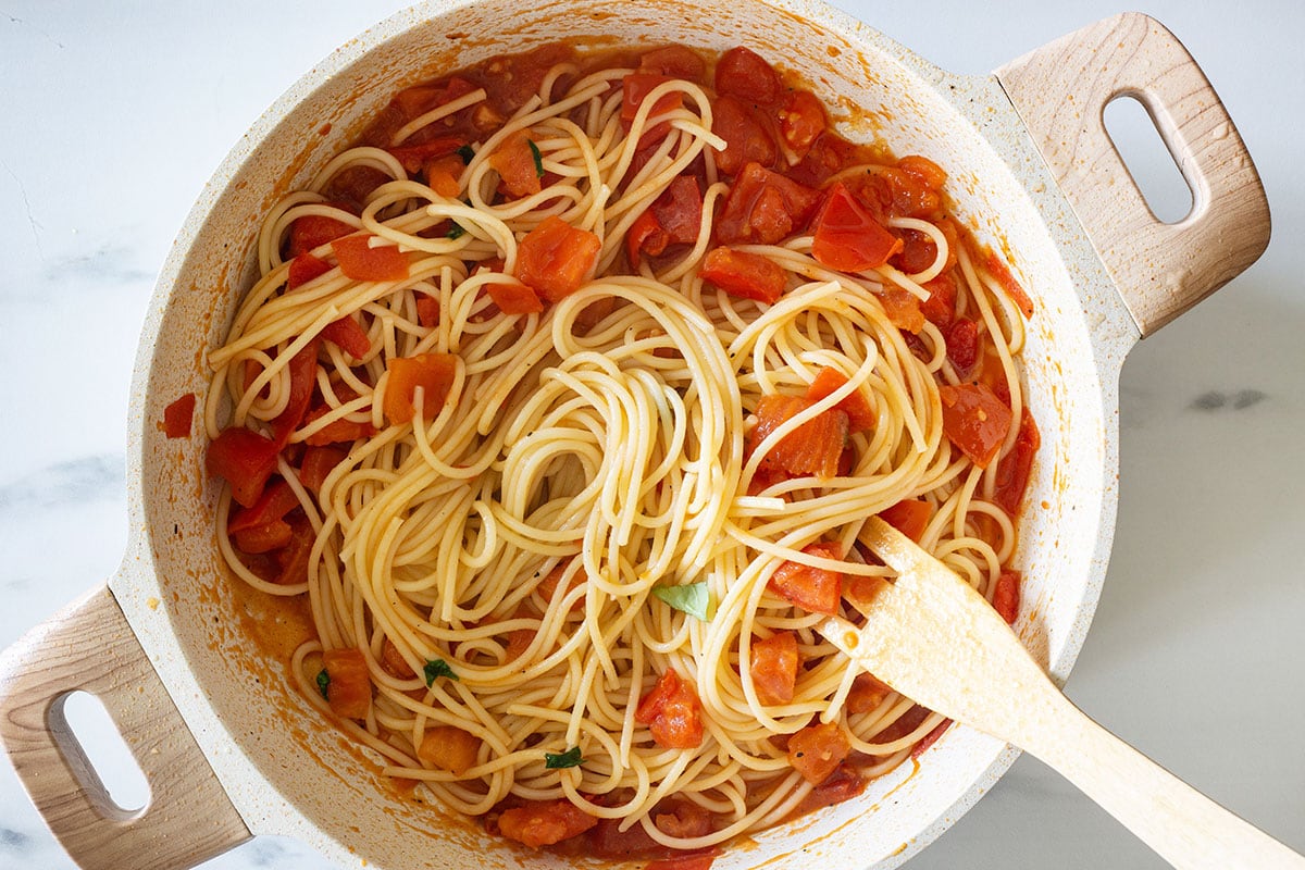 Spaghetti al pomodoro fresco being mixed in a pan.