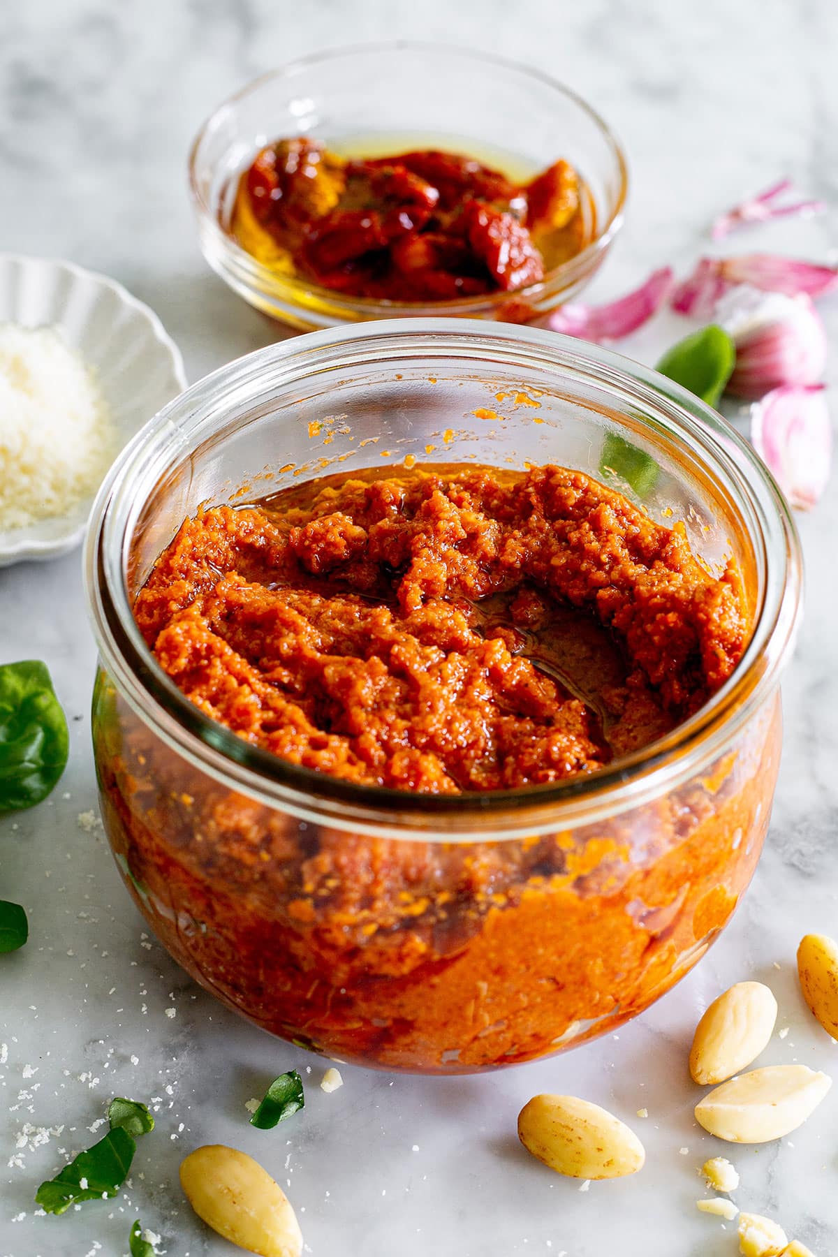 Sun-dried tomato pesto (pesto con pomodori secchi) in a jar with various ingredients around.