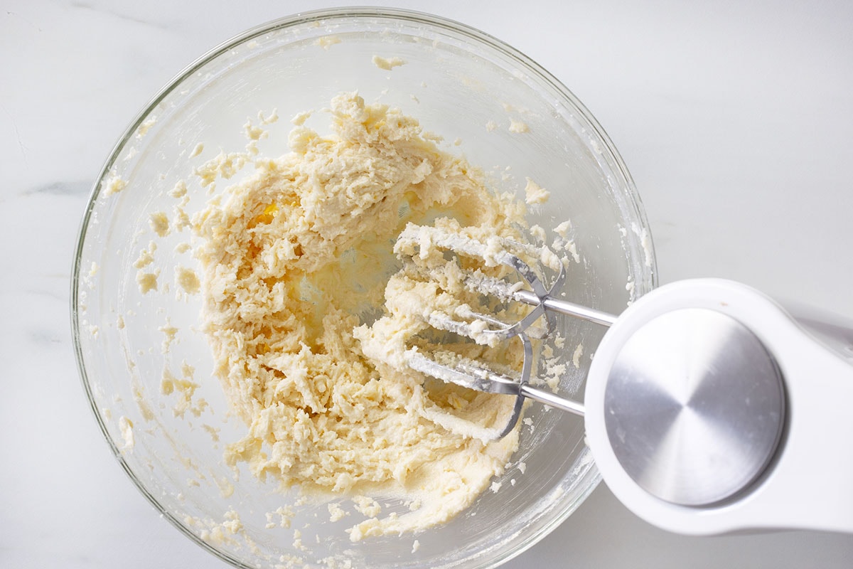 Mixing butter and sugar in a bowl with an electric mixer.