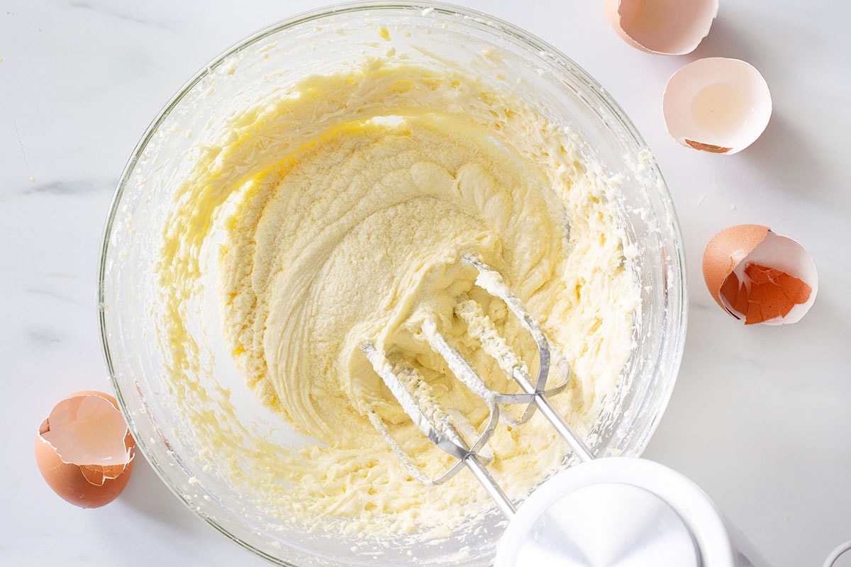Mixing eggs into the sugar and butter batter.