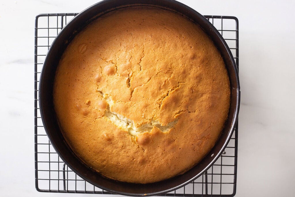 The baked torta margherita cake in the pan over a cooling rack.