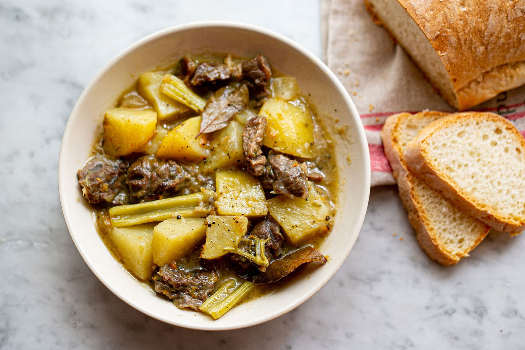 Beef spezzatino di manzo served in a plate with homemade bread on the side.