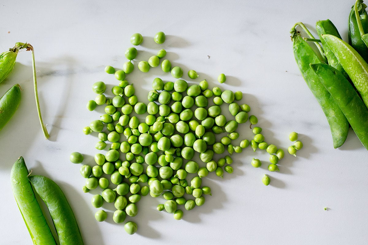 Fresh peas (piselli) on a  kitchen countertop.
