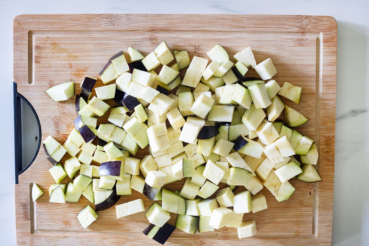 Eggplant cut into cubes on a cutting board.