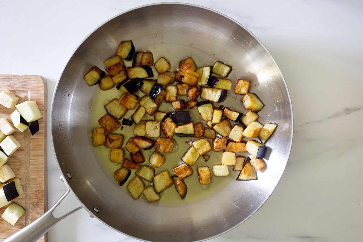 Frying eggplant cubes in a pan.