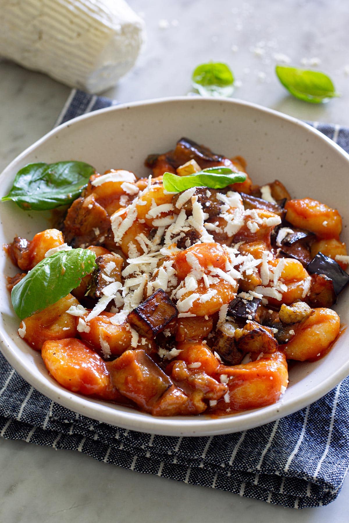Gnocchi alla Norma served in a plate with salty ricotta on top.